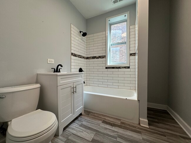 Fully renovated bathroom with subway tile tub surround and new vanity and toilet - 5653 S May St Unit 1