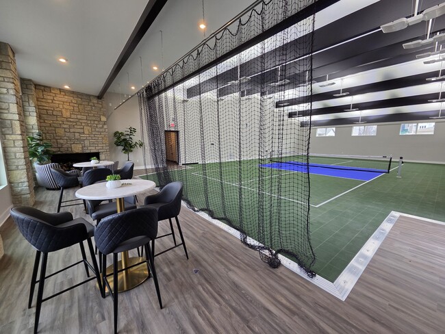 Indoor pickleball court with nearby seating and fireplace. - Flats at Sugar Run