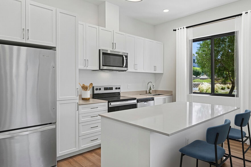 Freestanding Home kitchen with stainless steel appliances, white cabinetry, beige quartz countertops, and hard-surface flooring