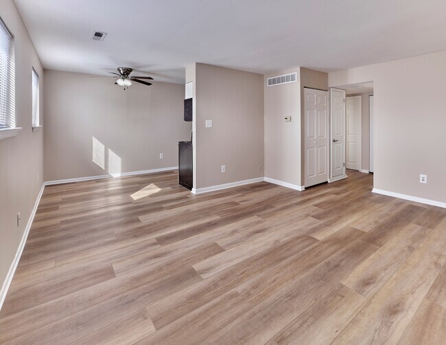 Modern open-concept living and dining space with stylish plank flooring at Village Square. - Village Square