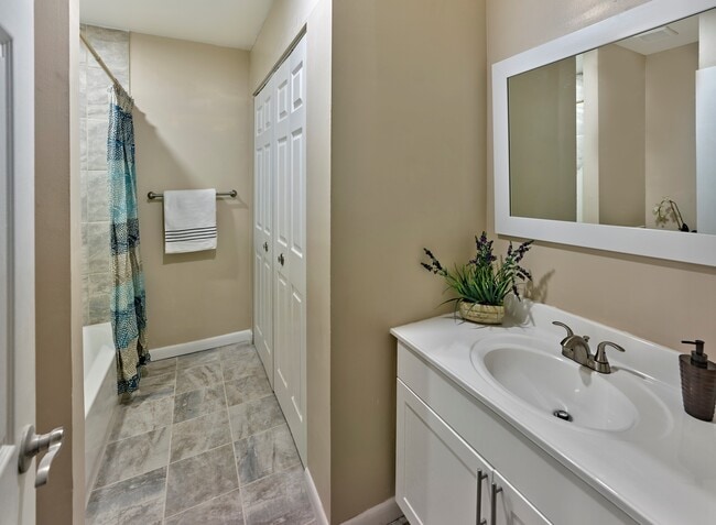 Stylish and updated bathroom at Haynes Run Apartments featuring sleek tile flooring, a spacious vanity, and neutral tones. - Haynes Run