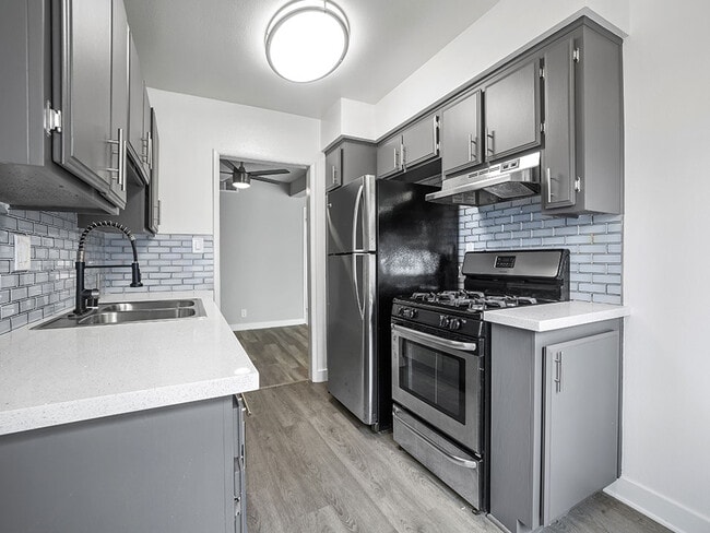 Tiled kitchen with stainless steel oven, fridge, and fixtures.