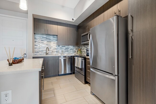 Model kitchen and dining room at our apartments in Boca Raton, featuring chairs around a table and counter seating.