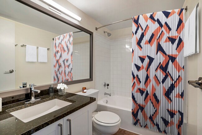 Renovated Package II bath with new white cabinetry, granite countertops, and hard surface flooring - AVA Van Ness