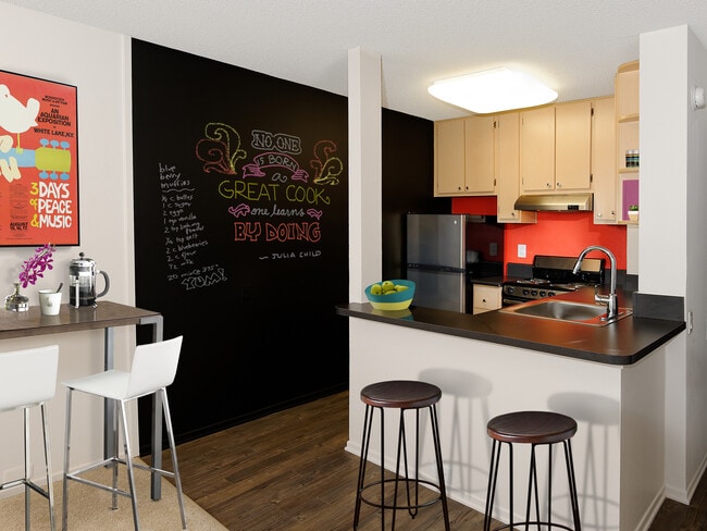 Classic Package III kitchen with stainless steel appliances, black laminate countertops, oak cabinetry, and hard surface flooring - AVA Pacific Beach