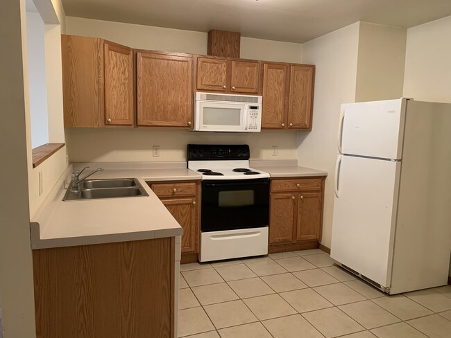 Kitchen with dishwasher, microwave and tile flooring. - 410 3rd St W Townhome