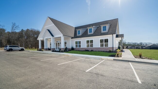 Exterior de la casa club con amplio estacionamiento y mecedoras en el porche delantero. - The Cottages at Battlefield Crossing