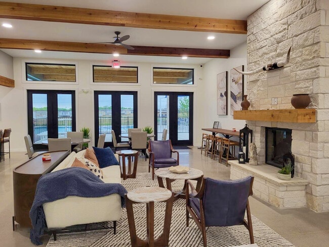 Clubhouse with leather chairs, soft seating, marble tables, and a stone fireplace topped with a longhorn skull decor