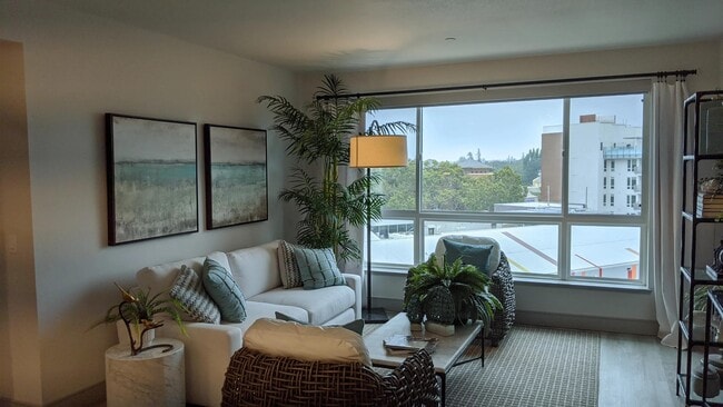 Cozy living area with oversized windows, wood-style plank flooring, and greenery creating a calming space for everyday comfort.