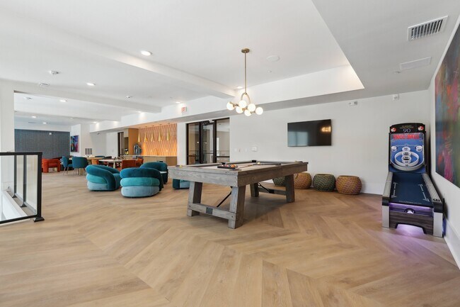 Salón social con televisores, juegos y espacios de relajación. - Brea Lakewood Ranch
