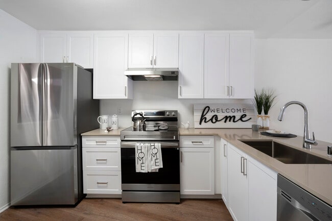Renovated Package I kitchen with stainless steel appliances, light grey quartz countertops, white cabinetry, and hard surface flooring