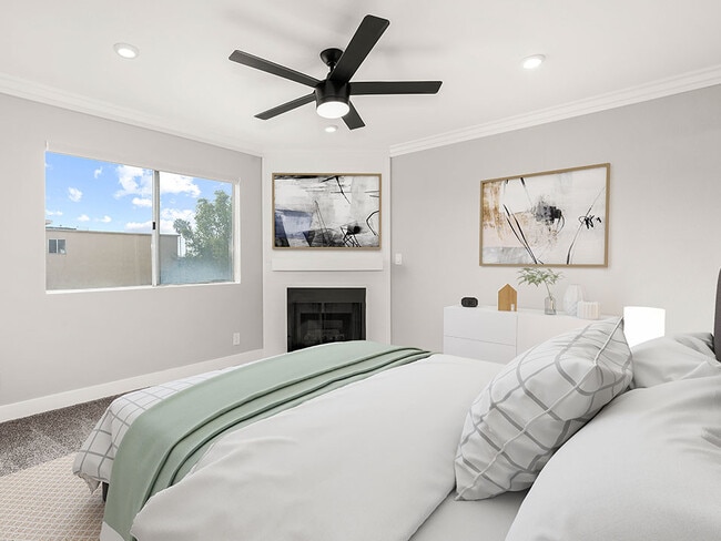 Carpeted bedroom with ceiling fan and private fireplace.