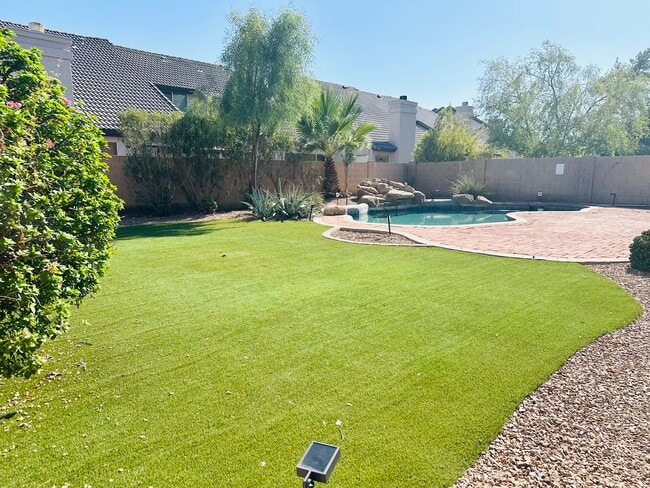 Low-maintenance backyard with artificial turf, a paver patio, and private pool.