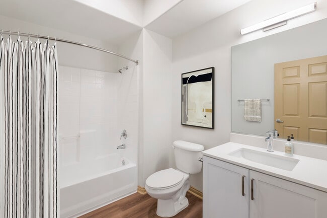 Renovated Package I bath with white speckled quartz countertop, white cabinetry, and hard surface flooring