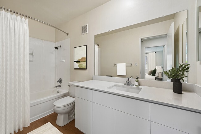 Renovated Package II bath with white quartz countertop, updated white cabinetry, and hard surface flooring