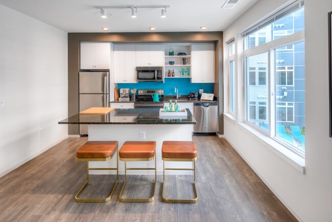 Kitchen with white cabinetry, granite countertops, island, stainless steel appliances and hard surface flooring