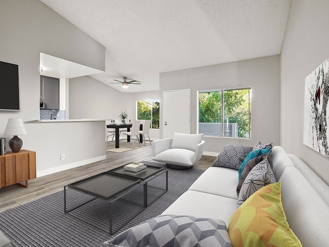 Hardwood floored living room with large windows and view of kitchen. - Corbin Terrace Apartments