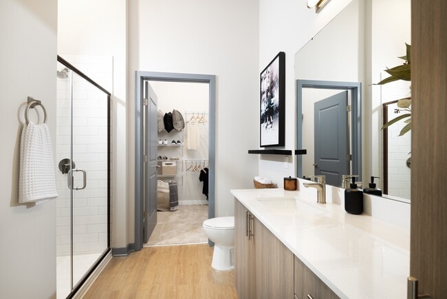 Primary bathroom with standing shower, oak cabinetry, white quartz countertops, and ample storage