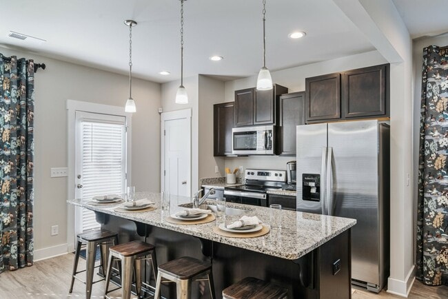 Cocina con electrodomésticos de acero inoxidable e isla. - Covey Homes Greene