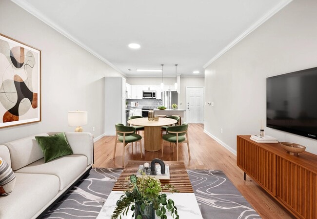 Open living and dining space with warm wood-style flooring, a connected kitchen, and a versatile layout.