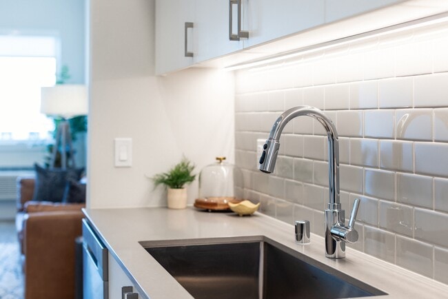 Kitchen with grey quartz countertops, white cabinetry, and grey subway tile backsplash