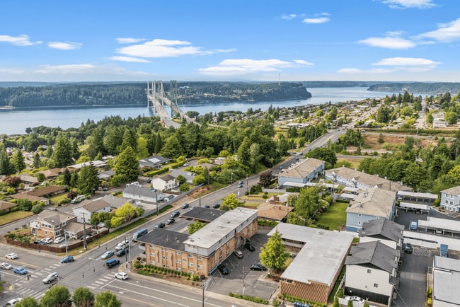 The iconic Tacoma Narrows Bridge connects Tacoma to the Kitsap Peninsula, surrounded by scenic residential neighborhoods and lush greenery.