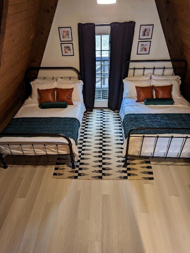 Un dormitorio bien iluminado con dos camas individuales, tonos neutros y una alfombra geométrica moderna. - 2406 Crockett Cir