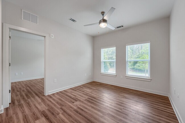 Bedroom with windows and ceiling fan and door leading to living room