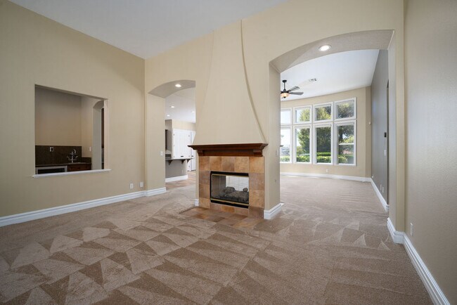 Living room and family room separated by cozy 2-way fireplace with a wet bar - 2850 Bronzino Ct