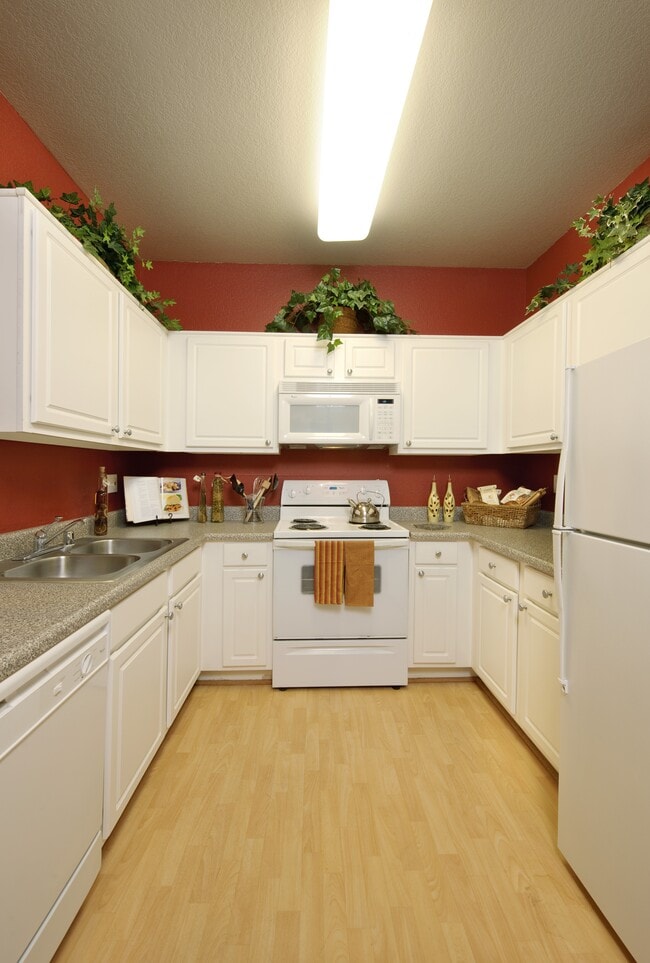 Kitchens with white appliances, grey speckled laminate countertops, and white cabinetry