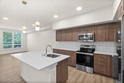 Contemporary kitchen with island, quartz countertops, stainless appliances, and pendant lighting.