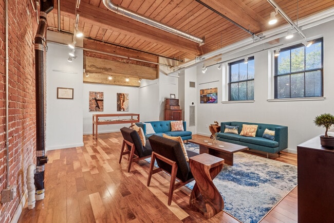 Loft-style apartment living room with exposed wood ceilings, large windows, and open-concept layout