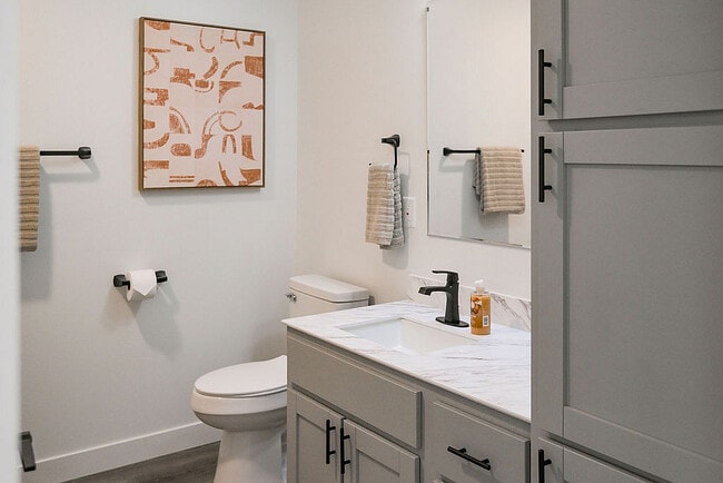 Baño moderno con accesorios elegantes, que incluye un tocador elegante, arte de pared abstracto elegante y gabinetes contemporáneos.