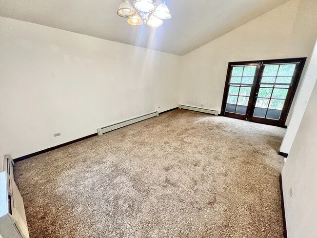 Bright living space with plush carpeting and elegant French doors, offering a cozy and inviting atmosphere. - Char Rose