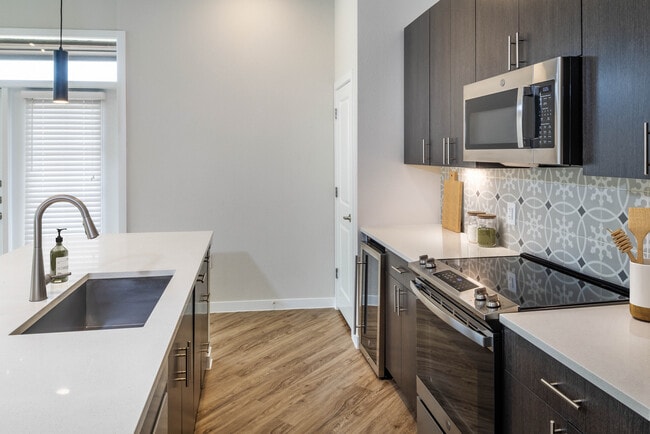 Kitchens with stainless steel appliances, wine fridges, quartz countertops, tile backsplash, and hard surface flooring