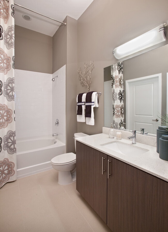 Bathroom with white quartz countertop, espresso cabinetry and hard surface flooring - Avalon Potomac Yard