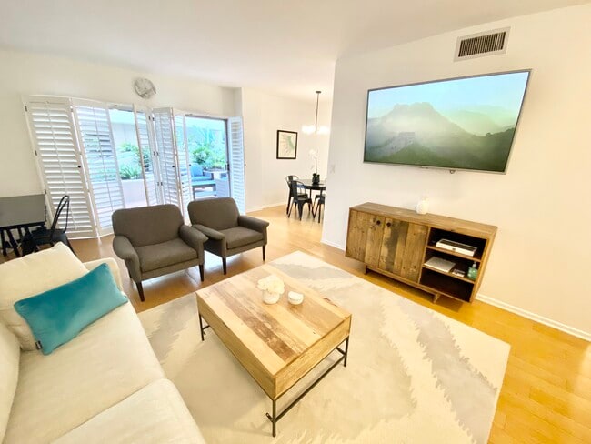 Sala de estar amueblada con pantalla plana, escritorio y puertas de patio. - 1131 Alta Loma Rd Unidad 123
