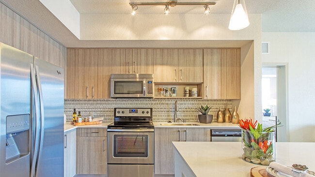 Luxury apartment kitchen with wood cabinetry, stainless steel appliances, and quartz countertops - Griffis North Olive