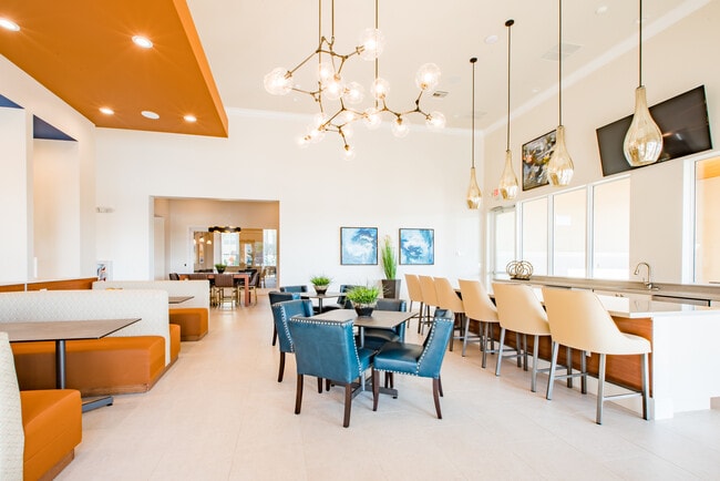 Salón para residentes con mesas de comedor, cocina pequeña y asientos en el bar.