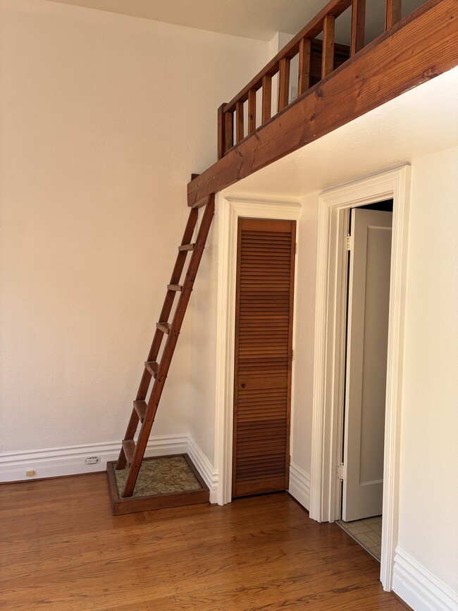 Escalera al altillo, armario de almacenamiento y puerta al baño.