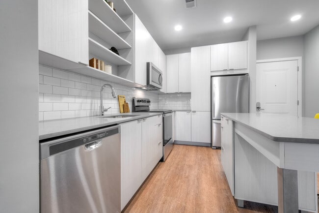 Kitchen with quartz stone countertops and white cabinetry with tile backsplash on hard surface flooring