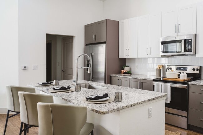 Gourmet kitchens with granite countertops and tile backsplashes - Modera Frisco Square Apartments