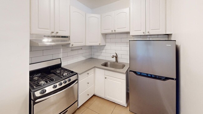 Kitchen with multiple cabinets, refrigerator, stove, range hood, and sink - 645 Stockton Street Apartments