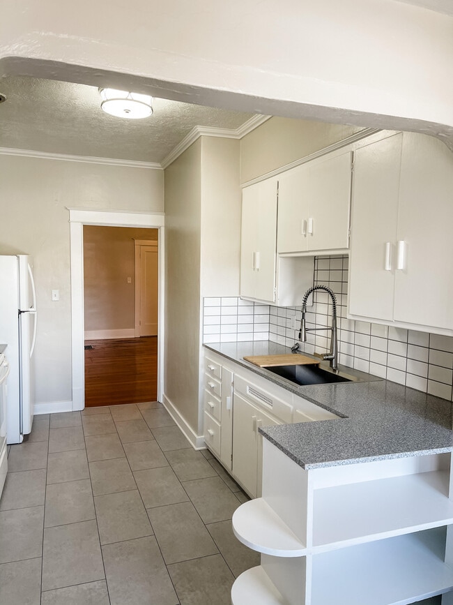 Kitchen with large sink and tile backsplash. - 6 Nineteen Apartments